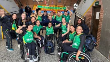 Jogadoras da seleção brasileira feminina de basquete em cadeira de rodas comemoram reunidas com bandeira do Brasil