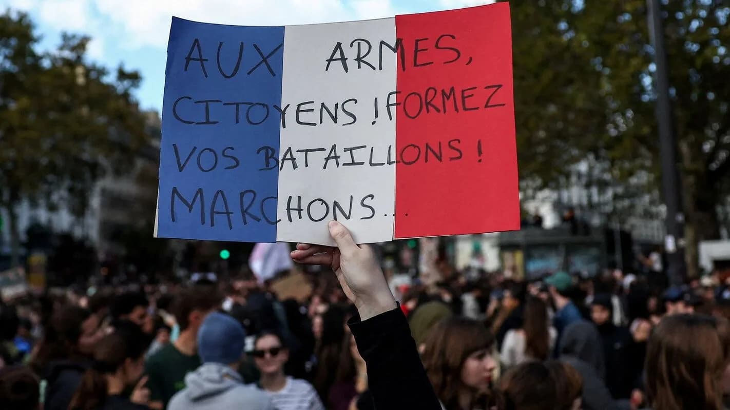 Manifestante segura cartaz com a bandeira da França durante protesto