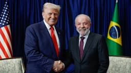 Lula e Trump apertam as mãos diante das bandeiras do Brasil e dos Estados Unidos, em foto de arquivo de outubro de 2025