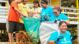 Grupo de pessoas separando material reciclável, incluindo plásticos, em programa de coleta