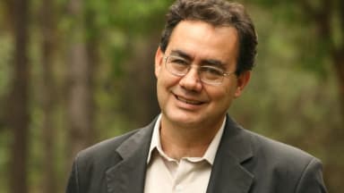Retrato de Augusto Cury sorrindo, de óculos e blazer escuro, em imagem de arquivo