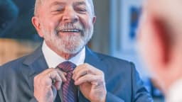 Lula sorri enquanto ajeita a gravata antes de entrevista de TV, em foto de arquivo de 2022