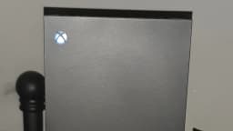 Console Xbox Series X com logo iluminado e controle em primeiro plano