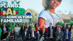 Produtora rural sorri em frente a banner do Plano Safra da Agricultura Familiar