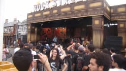 Multidão fotografa banda se apresentando no palco Rock Street, com estrutura decorada em estilo retrô
