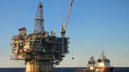 Plataforma de petróleo e gás no mar, com embarcação de apoio ao lado