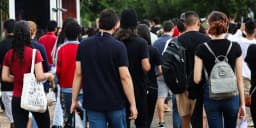 Candidatos de costas caminham com mochilas em direção a um local de aplicação de provas, foto de arquivo