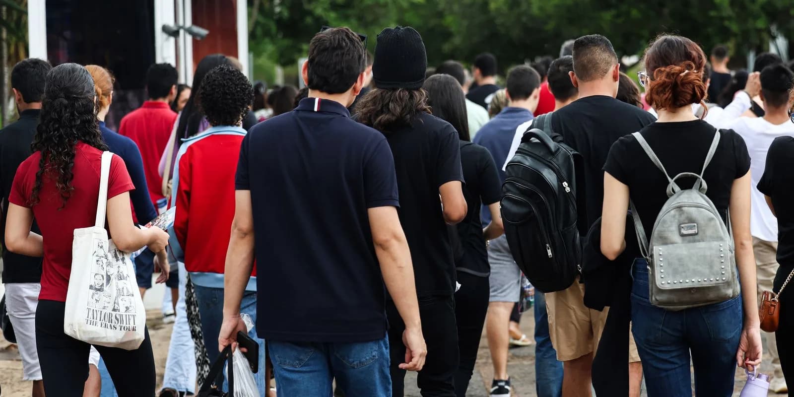 Candidatos de costas caminham com mochilas em direção a um local de aplicação de provas, foto de arquivo