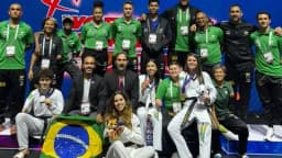 Delegação brasileira de parataekwondo posa em grupo com medalhas e bandeira do Brasil no Grand Prix de Muju