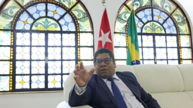 Embaixador de Cuba no Brasil, Victor Manuel Cairo Palomo, em entrevista com bandeiras de Cuba e do Brasil ao fundo