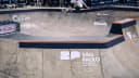 Skatista desce rampa de skate park em competição com logos da World Skate e Red Bull