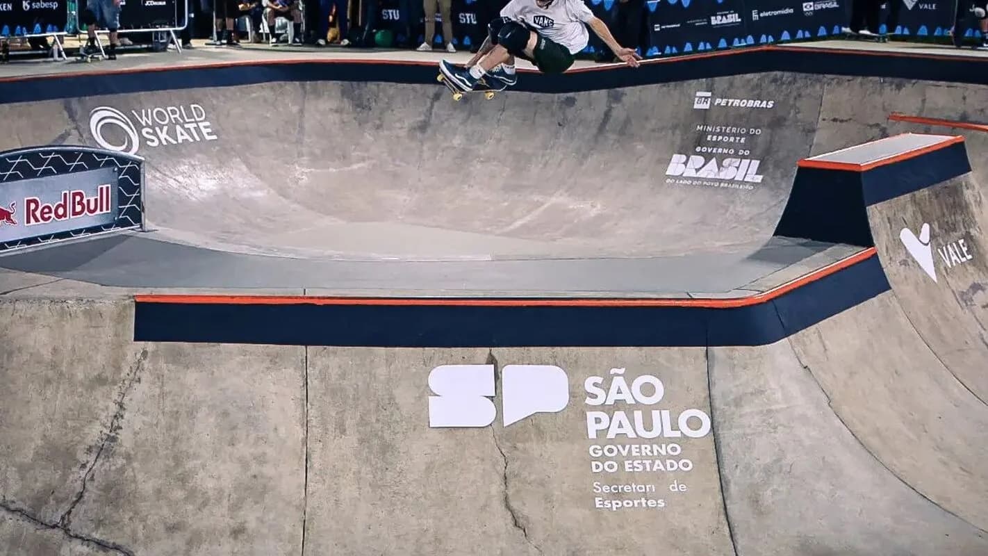 Skatista desce rampa de skate park em competição com logos da World Skate e Red Bull
