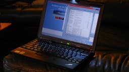 Notebook aberto e ligado, ilustrando o uso prolongado do computador conectado à tomada