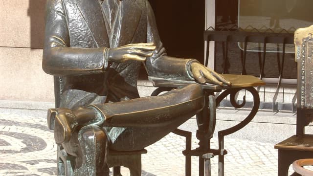 Estátua do escritor Fernando Pessoa sentado em pose contemplativa