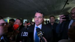 Senador Flávio Bolsonaro cercado por jornalistas e microfones durante entrevista coletiva