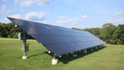 Painel solar fotovoltaico instalado em área gramada, conectado ao chão por estrutura metálica