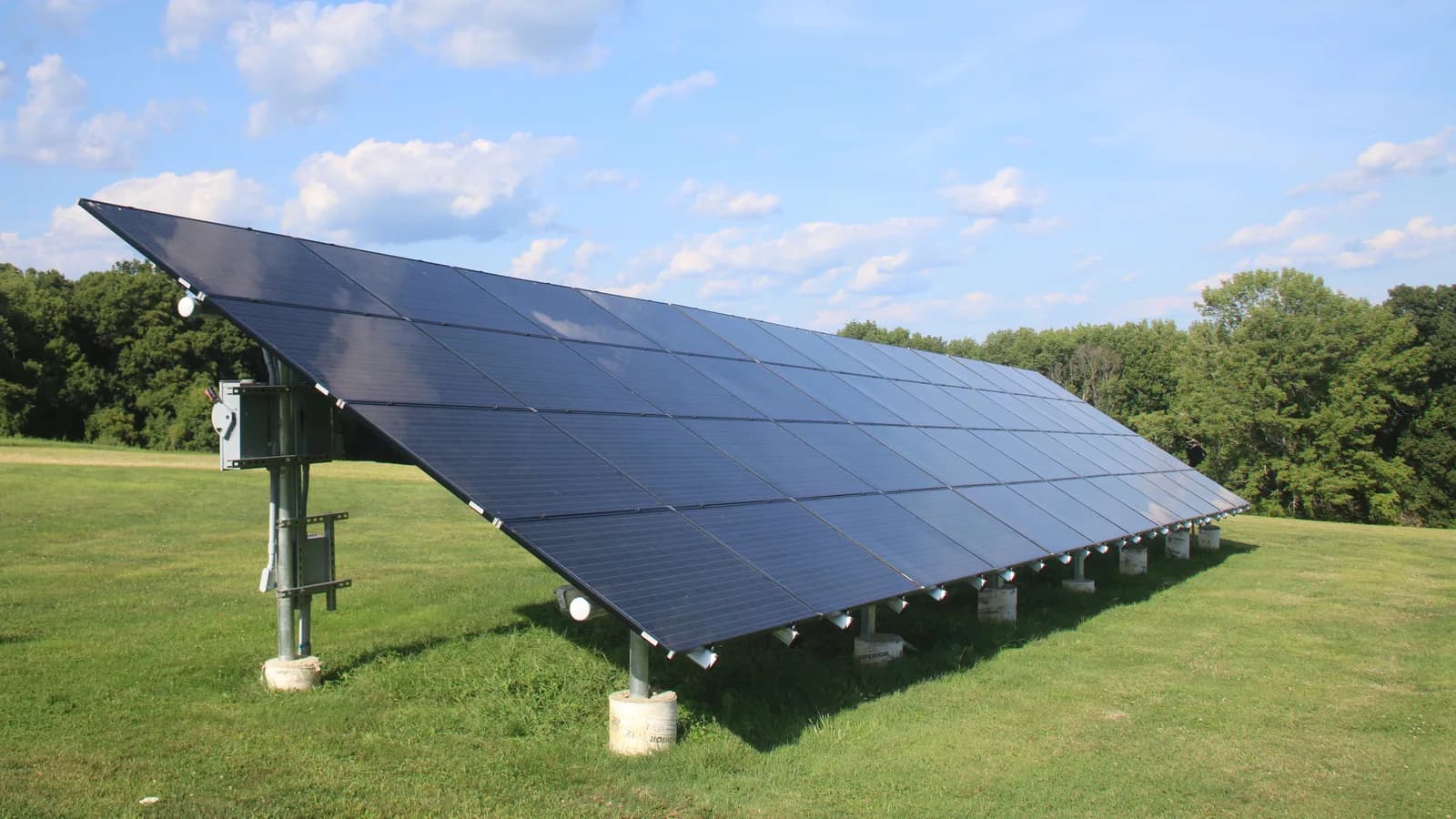Painel solar fotovoltaico instalado em área gramada, conectado ao chão por estrutura metálica