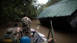Agentes do Ibama em fiscalização fluvial na Amazônia, em embarcação próxima a um barracão às margens do rio