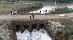 Vista aérea da barragem Santa Lúcia, com quatro galerias vertendo água, e equipes técnicas reunidas na estrada sobre a estrutura, entre Ilópolis e Putinga, no Rio Grande do Sul