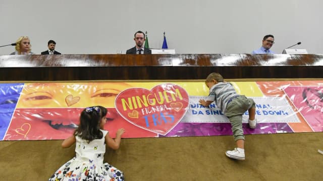 Duas crianças brincam em frente a uma faixa colorida sobre inclusão em evento no Senado Federal