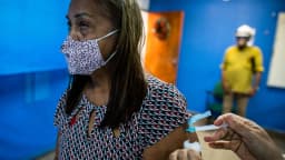 Idosa recebe dose de vacina em posto de saúde