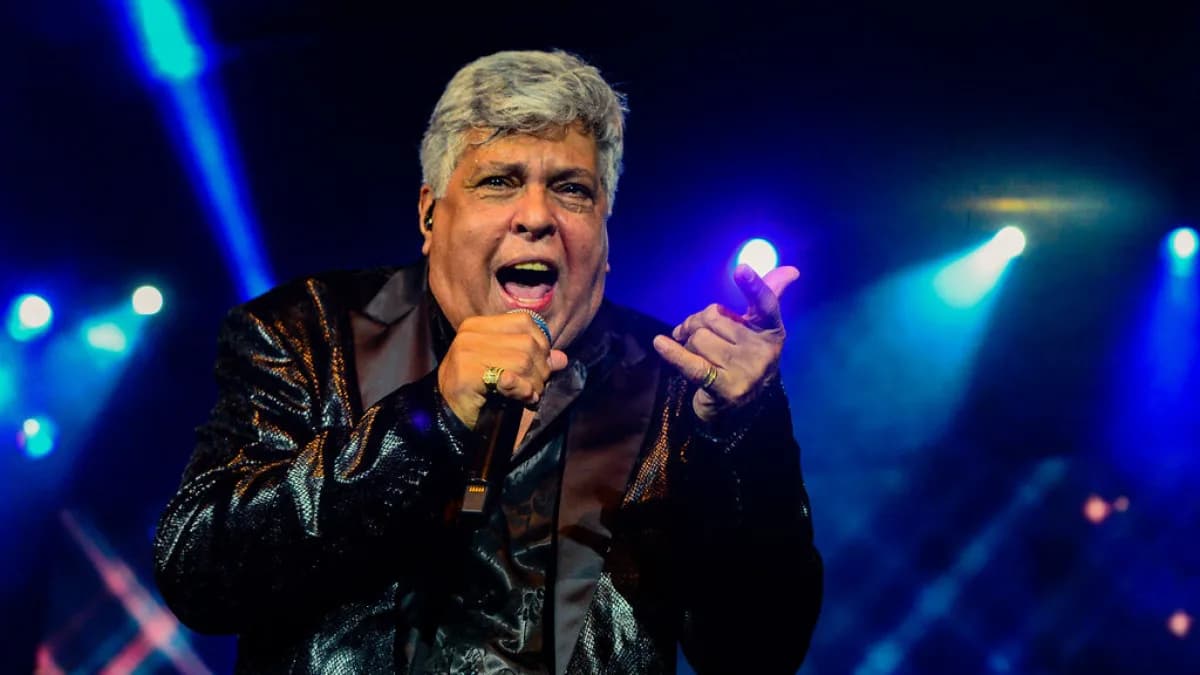 Sidney Magal cantando ao microfone em show iluminado por luzes azuis