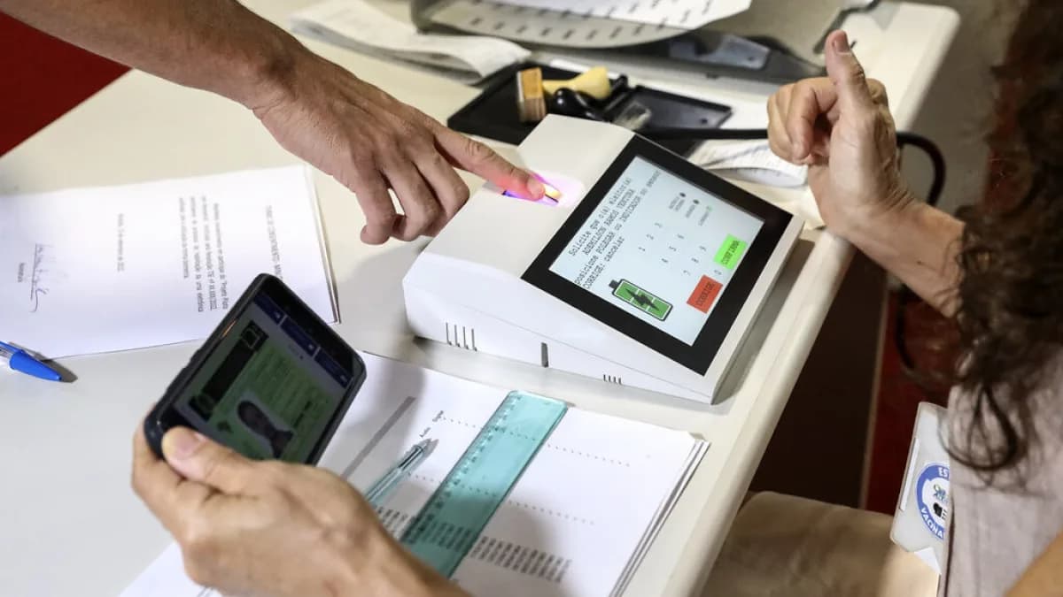 Mãos operam urna eletrônica com leitor biométrico durante simulação de teste de integridade