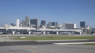 Vista do pátio e da pista do Aeroporto Santos Dumont, no Rio de Janeiro, com aviões estacionados e o centro da cidade ao fundo