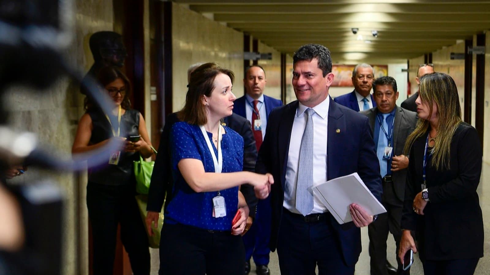 Senador Sergio Moro caminha por corredor do Senado cercado de assessores e jornalistas