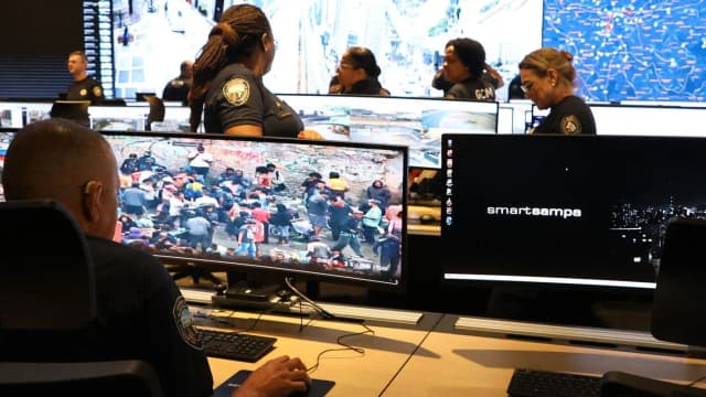 Sala de videomonitoramento com policiais acompanhando câmeras de segurança em telas