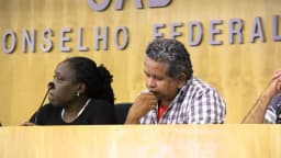 Pessoas em mesa de evento institucional com o letreiro do Conselho Federal da OAB ao fundo
