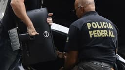 Agente da Polícia Federal carrega maleta durante operação contra lavagem de dinheiro