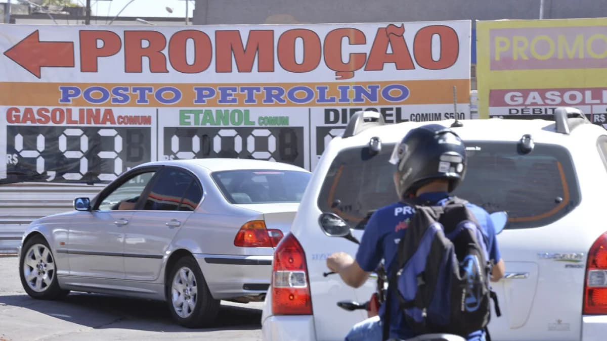 Posto de combustível no Brasil com placas de preço de gasolina e etanol, motociclista abastecendo