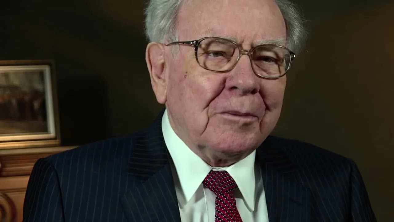 Warren Buffett em entrevista, de terno escuro e óculos