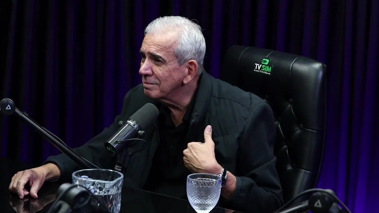 Ricardo Teagano sorri e faz sinal de positivo com o polegar durante a entrevista em estúdio