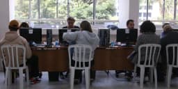 Pessoas sentadas em guichês de atendimento durante mutirão de renegociação de dívidas (foto ilustrativa, arquivo)