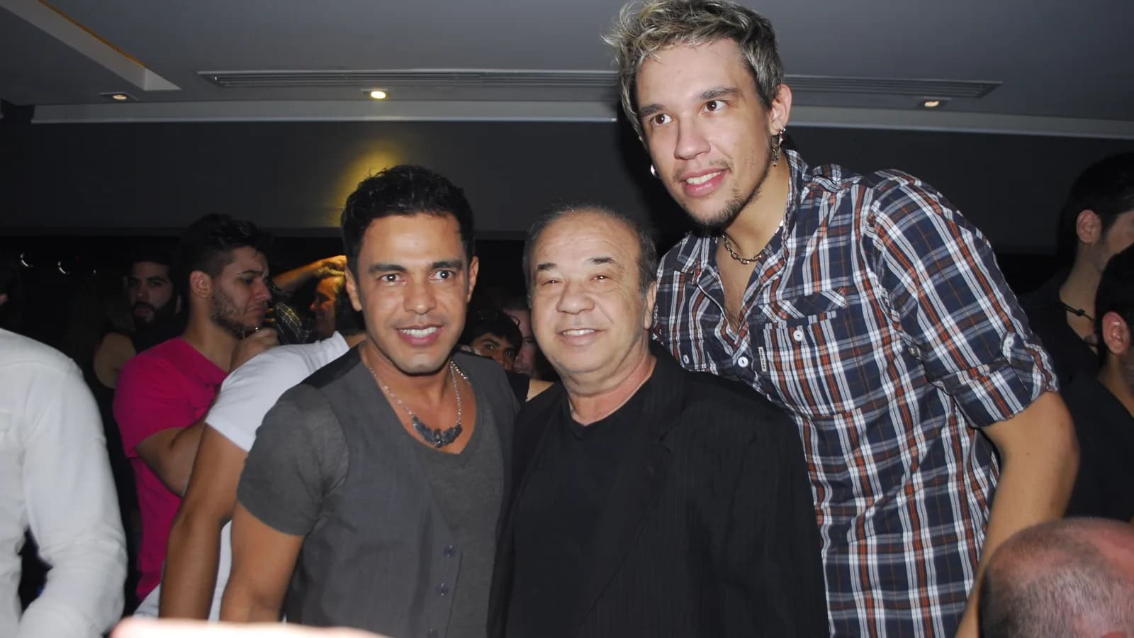 Zezé Di Camargo sorrindo ao lado de outras pessoas em evento