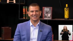 Douglas Ruas sorri durante entrevista em estúdio de TV, vestindo blazer azul