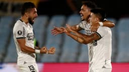 Jogadores do Botafogo comemorando gol em campo, uniforme branco com detalhes pretos