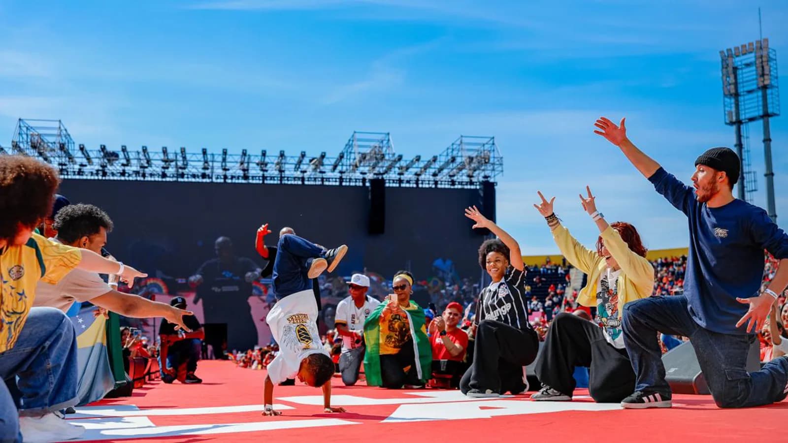 Apresentação cultural com dançarinos de rua em frente a multidão durante ato de campanha de Lula