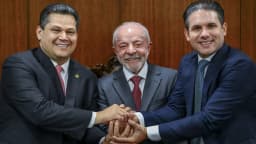 Lula sorri ao cumprimentar dois parlamentares em sessão solene de promulgação de emendas constitucionais na Câmara