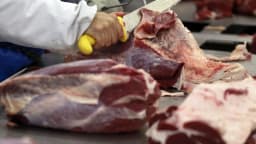 Trabalhador corta peça de carne bovina em frigorífico no Brasil