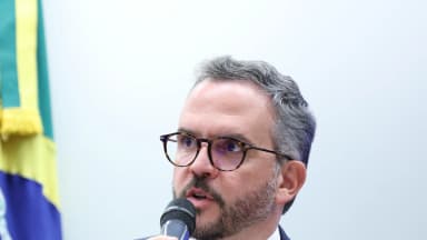 O ministro de Portos e Aeroportos, Tomé França, de óculos e terno azul-marinho, fala ao microfone durante audiência pública