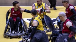 Jogador do Brasil disputa a bola com adversários do Canadá durante partida de rúgbi em cadeira de rodas
