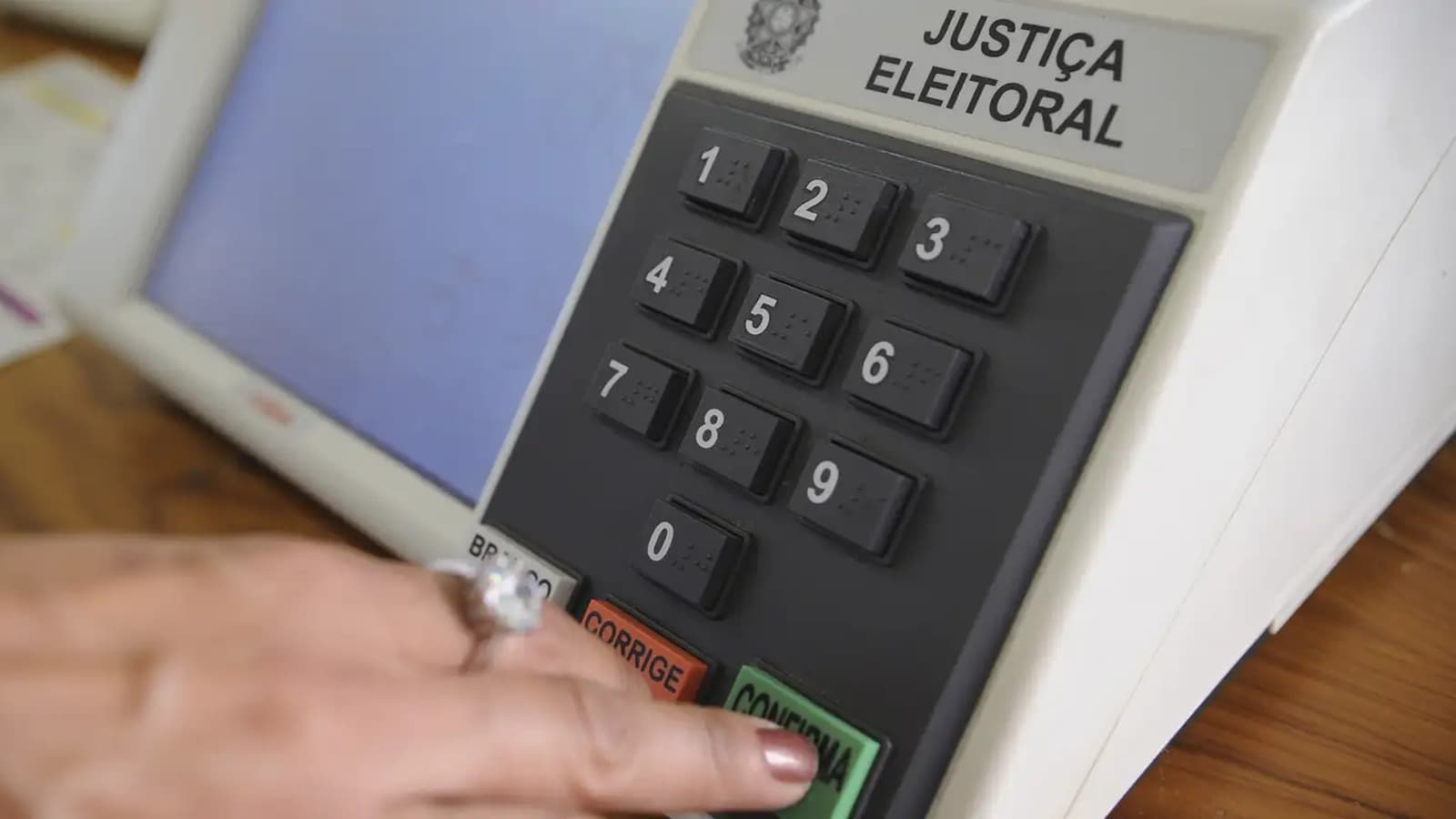Dedo de eleitora aperta a tecla confirma de uma urna eletrônica da Justiça Eleitoral, em imagem de arquivo