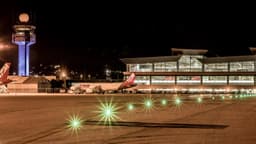 Pátio do Aeroporto Internacional de São Paulo, em Guarulhos, à noite, com a torre de controle iluminada, o terminal de passageiros ao fundo e luzes verdes de balizamento na pista. Imagem de arquivo.