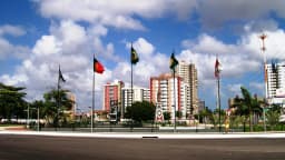 Vista da entrada da cidade de Fortaleza, no Ceará, com prédios e bandeiras ao fundo