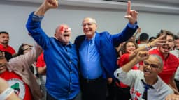 Lula sorri e ergue o punho ao lado de apoiadores em comemoração à reeleição