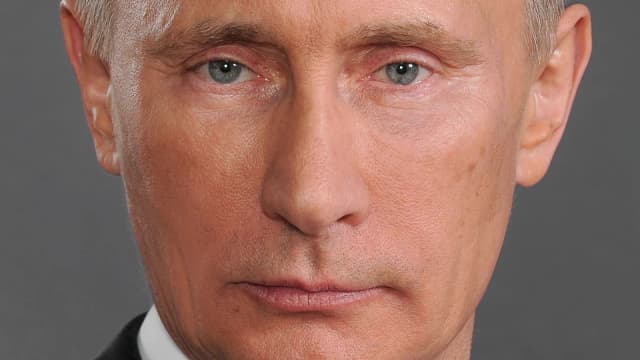 Vladimir Putin em foto oficial, de terno escuro e gravata vermelha