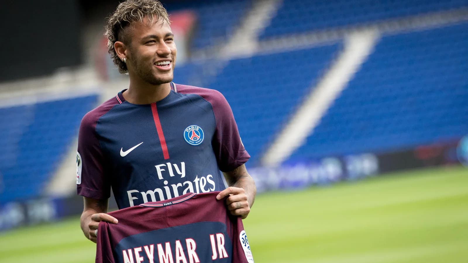 Neymar sorri segurando camisa em evento de apresentação, foto de arquivo